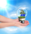 Green energy concept. Hands holding a lamp with a solar battery. Royalty Free Stock Photo